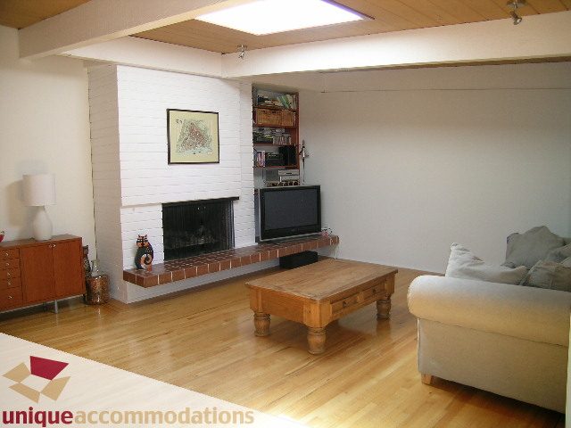 Furnished living room with hardwood floors, brick fireplace, and wooden countertops. - 2556 Belloc Street, North Vancouver