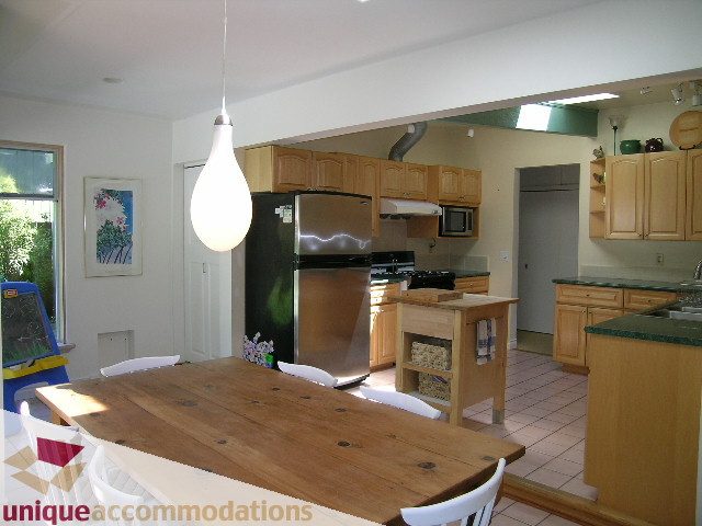 Bright kitchen with wooden countertops and a large island, featuring a stainless steel refrigerator and a modern pendant...