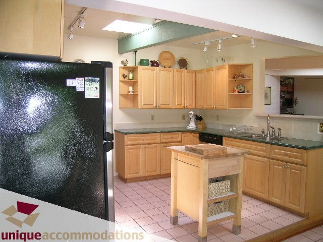 Bright kitchen with light wood cabinets, granite countertops, and a central island, featuring a modern and cozy ambiance.