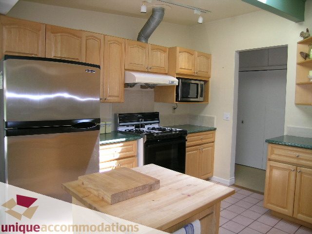 Bright kitchen with stainless steel appliances, granite countertops, and light wood cabinets. - 2556 Belloc Street, North Vancouver