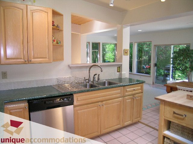 Bright kitchen with granite countertops and large windows, offering a view of the greenery outside. - 2556 Belloc Street, North Vancouver