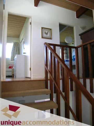 Staircase leading to upper level with wooden banisters and framed art on wall. - 2556 Belloc Street, North Vancouver