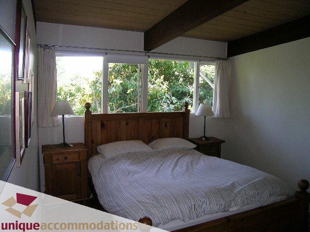 Bright bedroom with wooden furniture, large windows, and a view of greenery. - 2556 Belloc Street, North Vancouver
