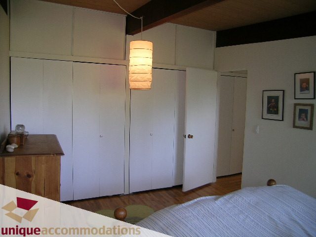 Furnished bedroom with white cabinets, hardwood floors, and a hanging light fixture. - 2556 Belloc Street, North Vancouver