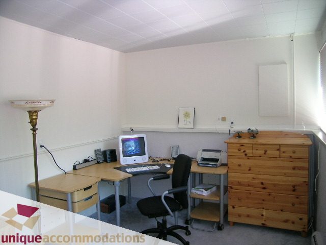 Bright home office with wooden desk, computer, and floor lamp. - 2556 Belloc Street, North Vancouver