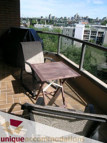Furnished balcony with city view, patio furniture, and brick wall. - 607 - 1490 Pennyfarthing Drive, Vancouver West Side