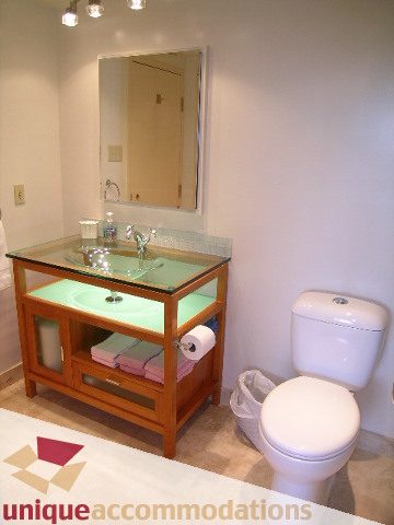 Bathroom with glass countertop and wooden vanity, clean and modern. - 607 - 1490 Pennyfarthing Drive, Vancouver West Side