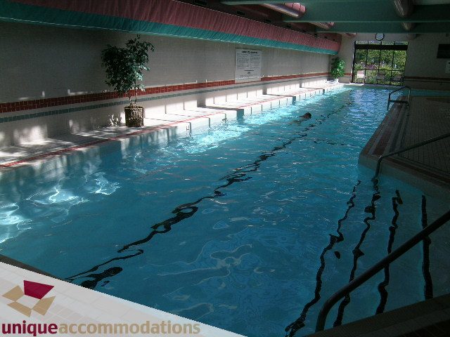 Spacious, sunlit indoor pool with tiled walls and steps leading into the water. - 607 - 1490 Pennyfarthing Drive, Vancouver West Side