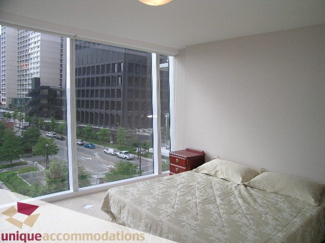 Furnished bedroom with large windows offering a city view, white bedding, and a cozy ambiance. - 502 - 1233 W. Cordova Street, Vancouver Downtown