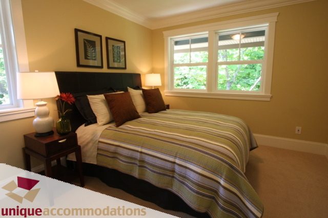 Spacious bedroom with large windows, striped bedding, and modern decor. - 1287 Sinclair Court, West Vancouver