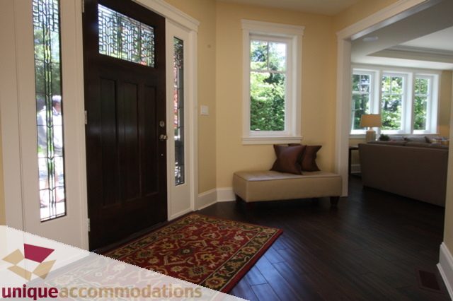 Furnished living room with hardwood floors and large windows, leading to a cozy seating area. - 1287 Sinclair Court, West Vancouver
