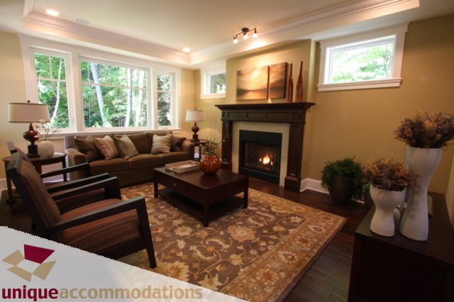 Furnished living room with large windows, patterned rug, and cozy seating. - 1287 Sinclair Court, West Vancouver