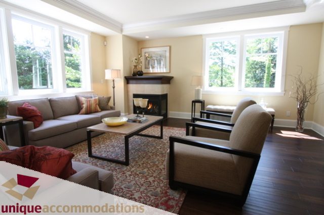 Bright living room with large windows, cozy sofa, and fireplace. - 1287 Sinclair Court, West Vancouver