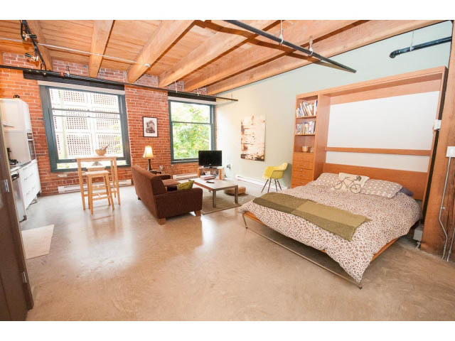 Furnished loft with exposed brick walls, hardwood floors, and a cozy living area. - 210 - 55 E Cordova St, Vancouver Downtown