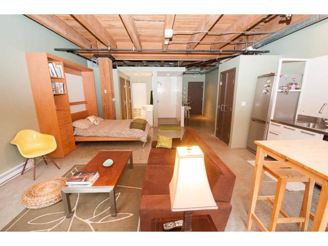 Open-concept loft with wooden ceiling, modern furnishings, and a cozy corner bed. - 210 - 55 E Cordova St, Vancouver Downtown