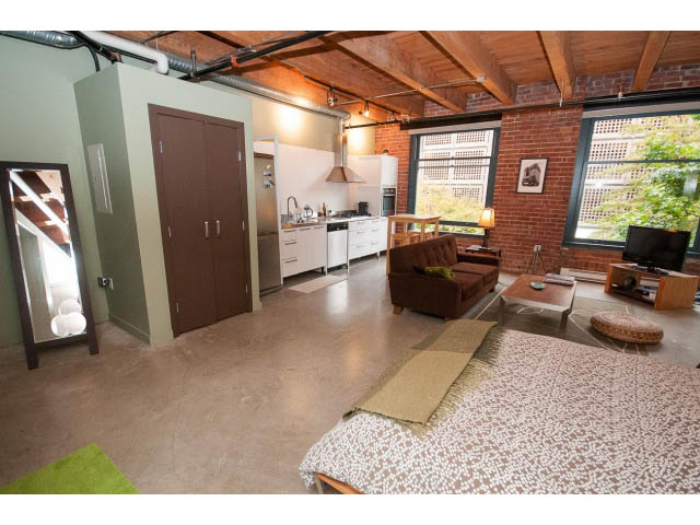 Bright loft with exposed brick walls, hardwood floors, and a city view through large windows. - 210 - 55 E Cordova St, Vancouver Downtown