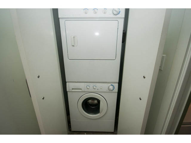 Bright laundry area with stacked washer and dryer, white walls. - 210 - 55 E Cordova St, Vancouver Downtown