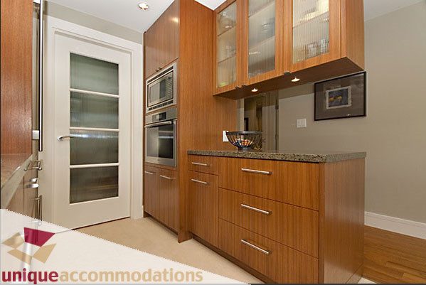 Bright kitchen with wooden cabinets, granite countertops, and stainless steel appliances. - 801- 628 Kinghorne Mews, Vancouver Downtown