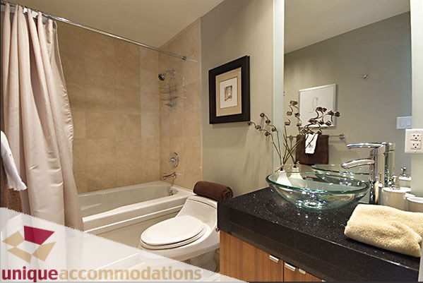 Furnished bathroom with glass vessel sink, dark countertop, and modern decor. - 801- 628 Kinghorne Mews, Vancouver Downtown