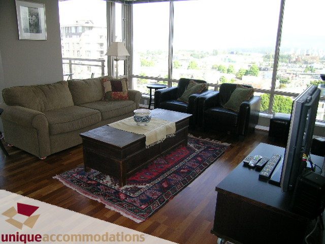 Furnished living room with hardwood floors, city view, and cozy seating. - 802-1590 West 8th Ave, Vancouver West Side