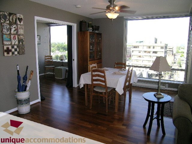 Spacious living room with hardwood floors, city view, and dining area. - 802-1590 West 8th Ave, Vancouver West Side