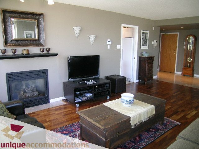 Furnished living room with hardwood floors, a fireplace, and a large TV. - 802-1590 West 8th Ave, Vancouver West Side