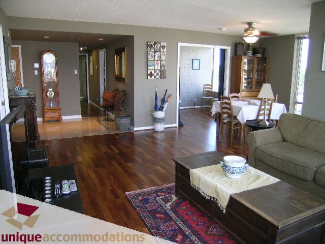 Spacious living room with hardwood floors, a cozy sofa, and a dining area in the background. - 802-1590 West 8th Ave, Vancouver West Side