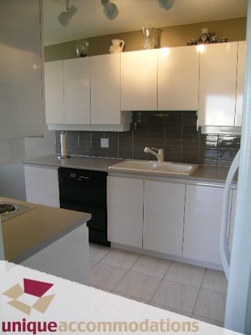 Bright kitchen with white cabinets, stainless steel countertops, and black tile backsplash. - 802-1590 West 8th Ave, Vancouver West Side