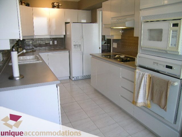 Bright kitchen with white cabinets, granite countertops, and a modern stove, featuring a cozy ambiance with a towel...