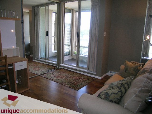 Furnished living room with hardwood floors, city view through sliding doors. - 802-1590 West 8th Ave, Vancouver West Side