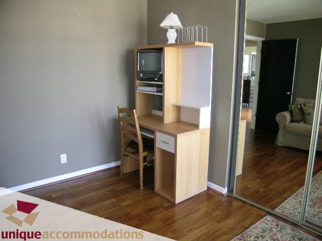 Furnished living room with hardwood floors and a desk setup. - 802-1590 West 8th Ave, Vancouver West Side