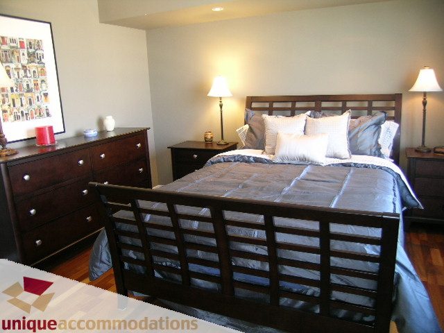 Furnished 2-bedroom + den with hardwood floors and a cozy bed setup. - 802-1590 West 8th Ave, Vancouver West Side