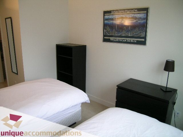 Furnished bedroom with two single beds, black nightstand, and framed artwork on the wall. - 184 Chesterfield Avenue, North Vancouver