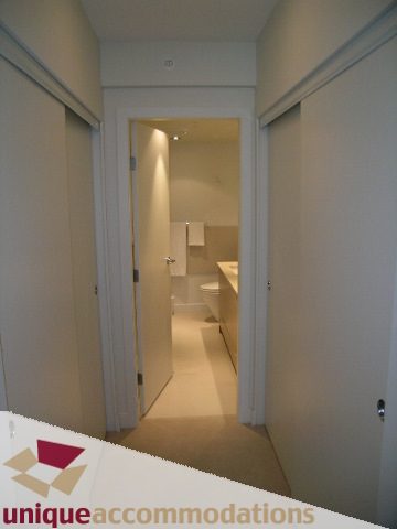 Bright hallway leading to a well-lit bathroom with white fixtures and a countertop. - 184 Chesterfield Avenue, North Vancouver