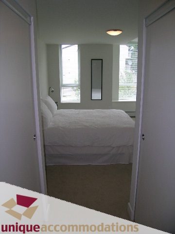 Bright bedroom with large windows and a mirror, showcasing a cozy and modern feel. - 184 Chesterfield Avenue, North Vancouver