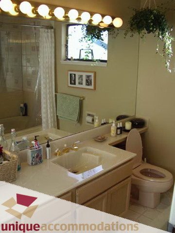 Bathroom with beige countertops and a large mirror above the sink. - 414 Kings Road  Mahon, North Vancouver