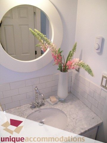 Bathroom with marble countertop and round mirror, fresh floral arrangement. - 1815 Creelman Avenue, Vancouver West Side