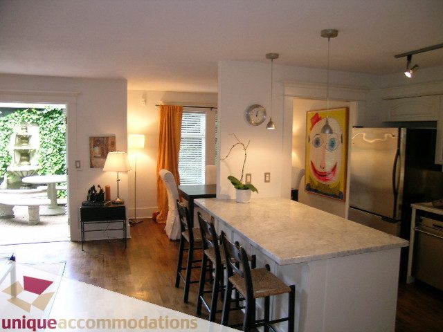 Bright kitchen with granite countertops and hardwood floors, featuring a unique abstract painting and pendant lighting.