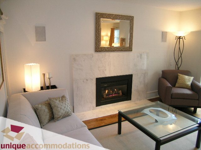 Furnished living room with marble fireplace, modern furniture, and glass coffee table. - 1815 Creelman Avenue, Vancouver West Side