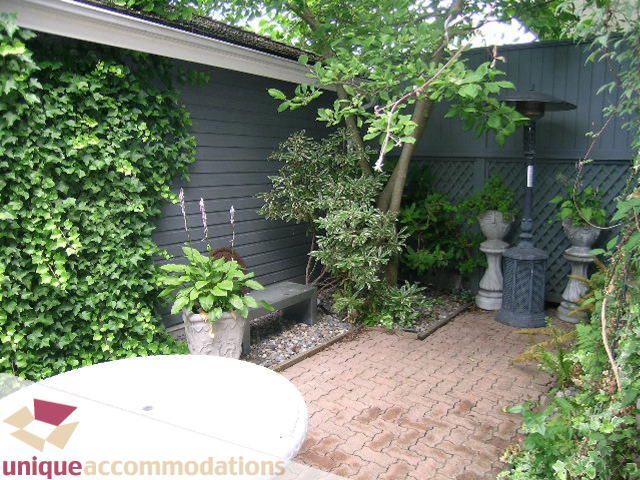 Furnished patio with brick path, ivy-covered walls, and potted plants. - 1815 Creelman Avenue, Vancouver West Side