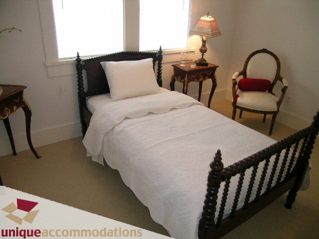 Bright bedroom with white bedding and wooden furniture, featuring a cozy reading nook. - 1815 Creelman Avenue, Vancouver West Side