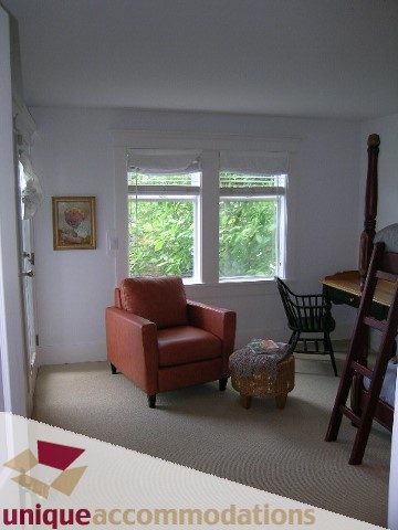 Bright living room with orange armchair and wicker basket, natural light from windows. - 1815 Creelman Avenue, Vancouver West Side