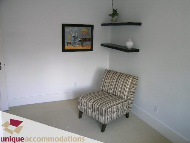 Furnished bedroom with striped armchair and floating shelves, minimalist decor. - 1815 Creelman Avenue, Vancouver West Side