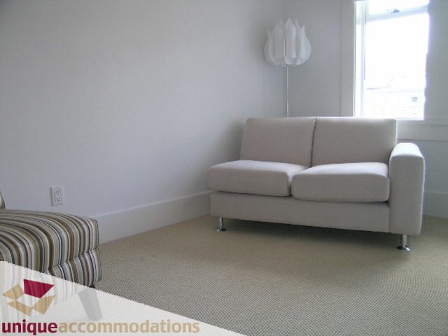Bright living room with modern white furniture and a large window. - 1815 Creelman Avenue, Vancouver West Side