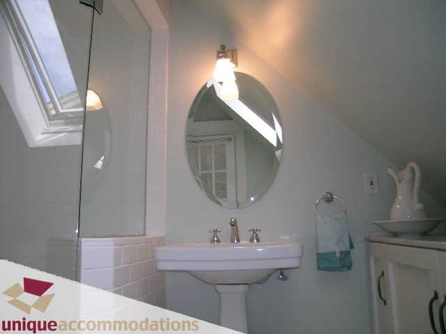 Bright bathroom with white sink, round mirror, and skylight. - 1815 Creelman Avenue, Vancouver West Side