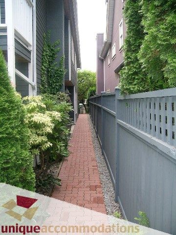 Fenced walkway leading to a 4-bedroom townhouse with brick path and greenery. - 1815 Creelman Avenue, Vancouver West Side