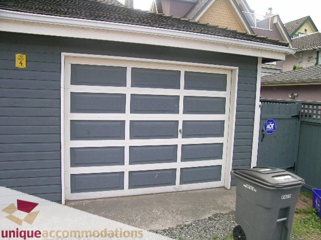 Furnished 4-bedroom townhouse with a gray garage door and a recycling bin in front. - 1815 Creelman Avenue, Vancouver West Side