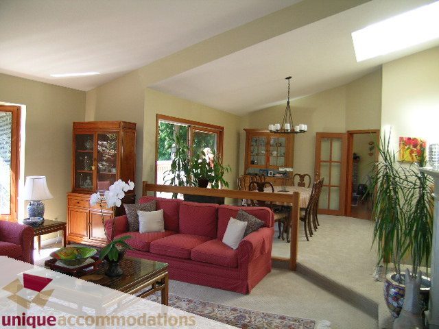 Spacious living room with red couches, wooden furniture, and large windows. - 2769 Ottawa Avenue, West Vancouver