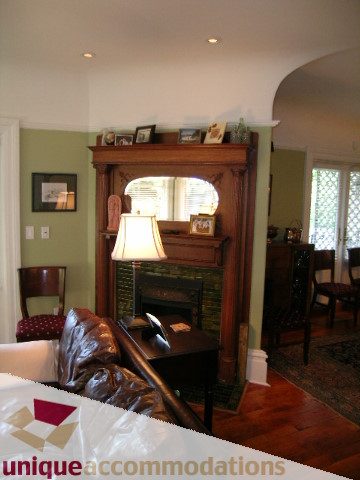 Furnished living room with arched fireplace, hardwood floors, and a cozy corner. - 995 Bute Street "Rand House", Vancouver Downtown