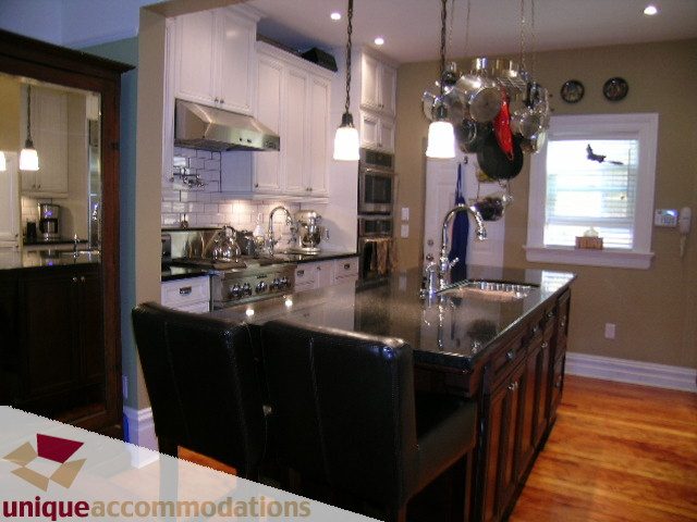 Bright kitchen with white cabinetry, stainless steel appliances, and hardwood floors. - 995 Bute Street "Rand House", Vancouver Downtown